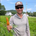Owner of Crossroad Farm, a local produce supplier for Woodstock Farmers' Market, holds carrots in his field.