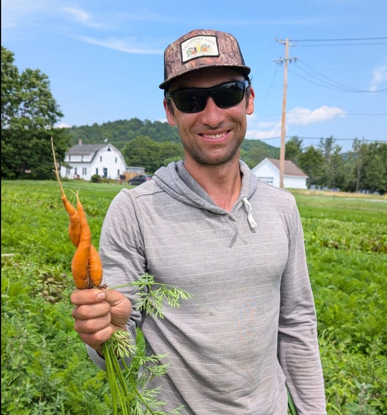 Owner of Crossroad Farm, a local produce supplier for Woodstock Farmers' Market, holds carrots in his field.
