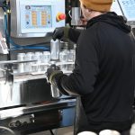 Stowe Cider available at Woodstock Farmers' Market. Image shows man in a beanie canning cider.